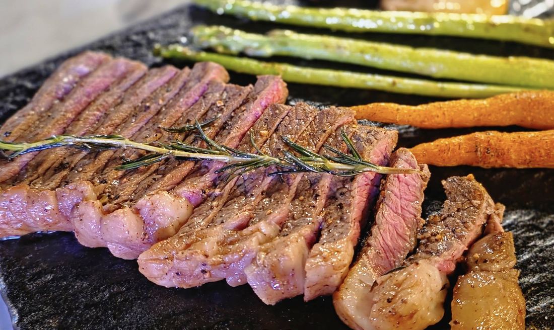 MOOD Bar — sliced grilled steak on a hot stone with asparagus and carrots